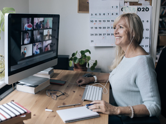 Eine Frau sitzt im Homeoffice und nimmt an einer Videokonferenz teil