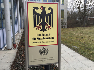 Zwei Schilder vor dem BfS-Gebäude in Neuherberg zeigen das BfS-Wappen und die Auszeichnung als WHO-Kooperationszentrum