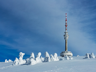 Ein Funkturm steht in einer verschneiten Landschaft.