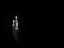 Three burning candles against a black background