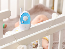 A cordless device monitoring a baby in its bed.
