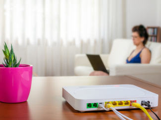 Router on a desk. Woman in the background sitting on a couch